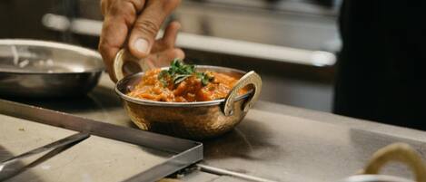 A person serving food from a metal bowl with a handle.