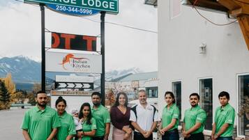 A group of people standing in front of a building with a sign that reads "Village Lodge" and a digital sign for "Indian Kitchen."