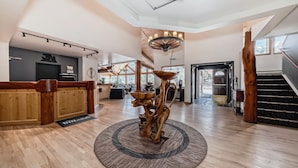 Un vestíbulo amplio con un mostrador de recepción de madera, una escultura de madera en el centro y una escalera.