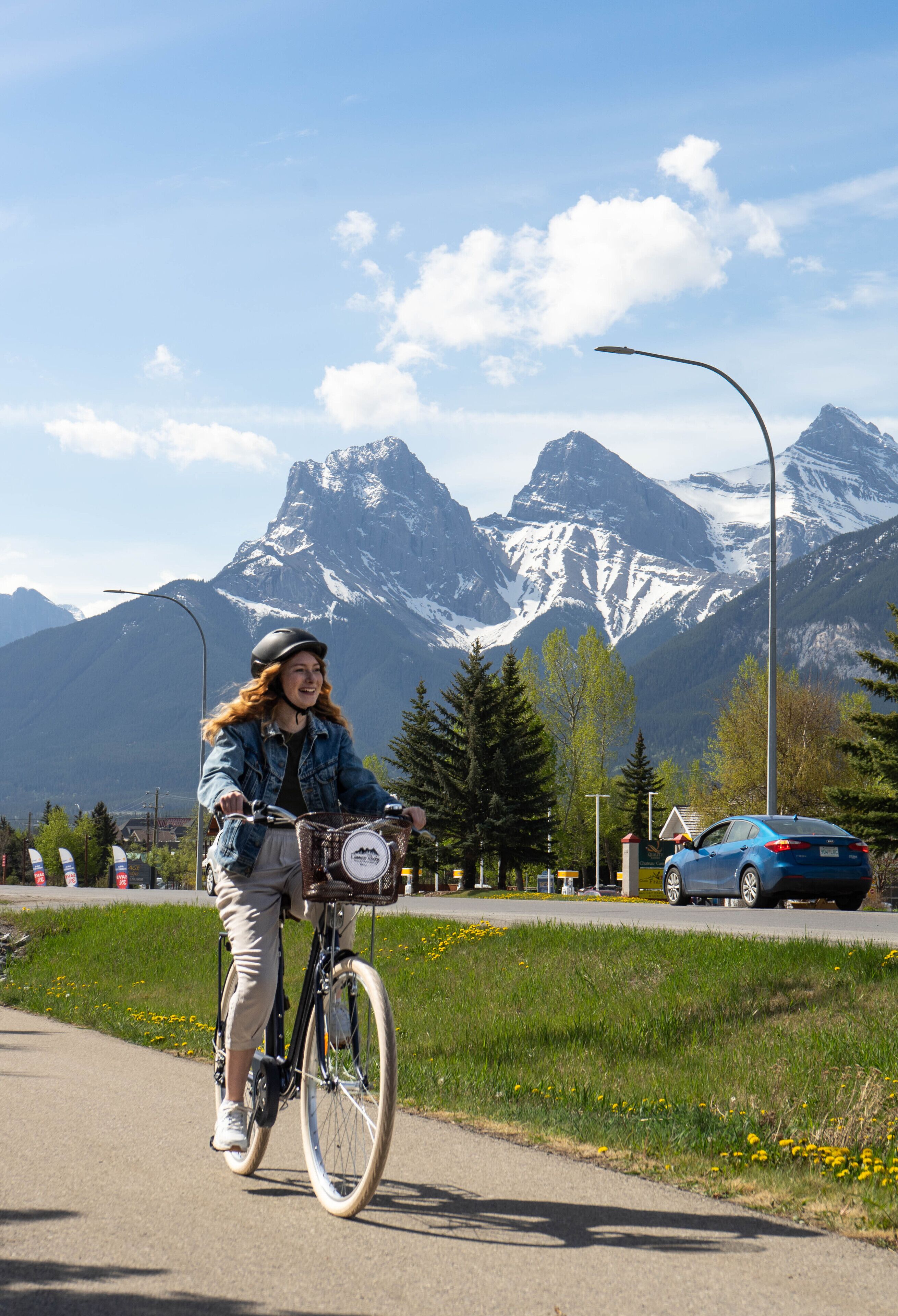 A person riding a bicycle on a paved path with a mountain backdrop.