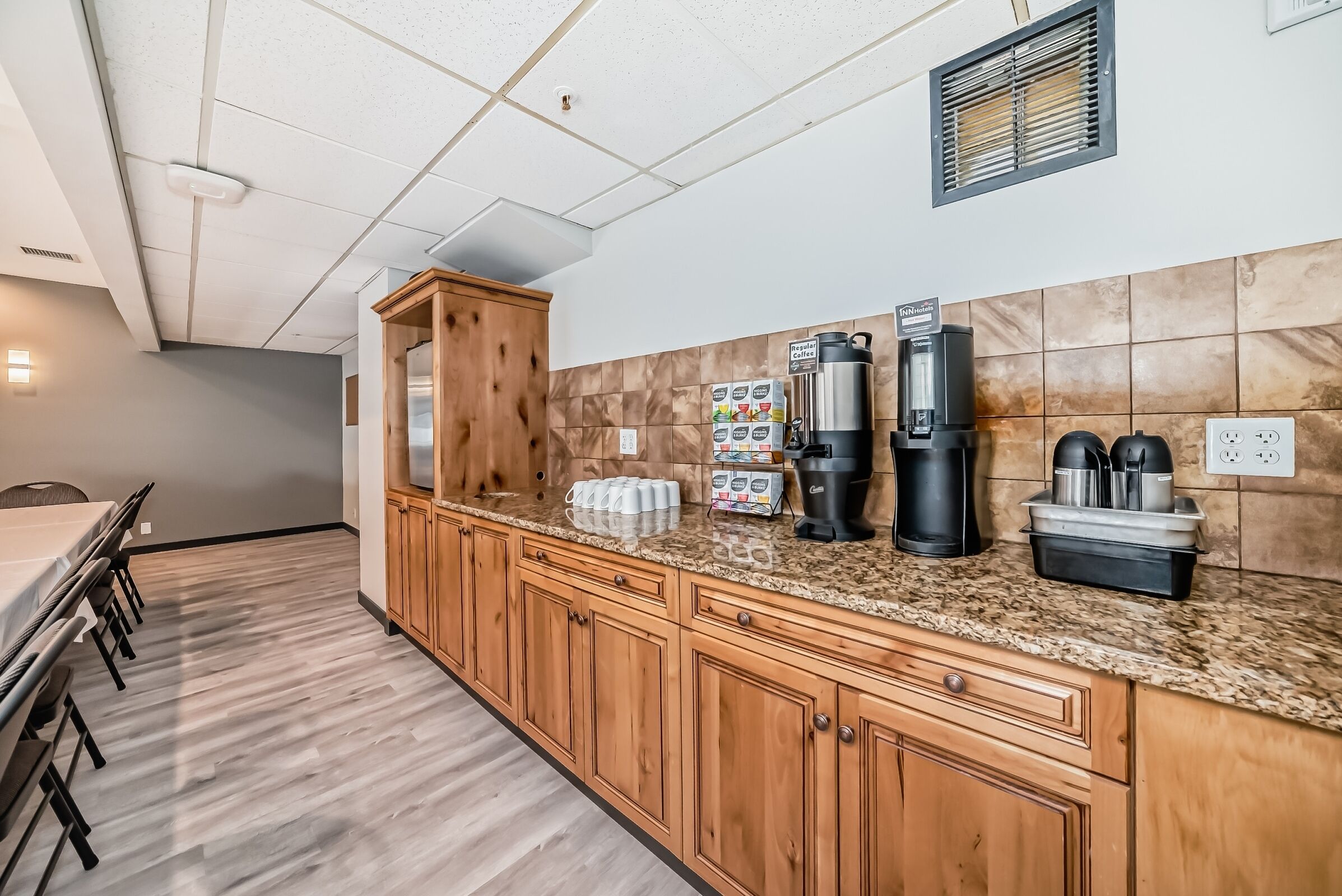 A kitchen with wooden cabinets, a granite countertop, and coffee-making equipment.