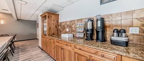 A kitchen with wooden cabinets, a granite countertop, and coffee-making equipment.