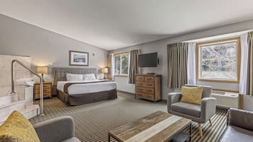 Habitación de hotel con cama, escritorio, silla, televisión, cómoda y ventana con cortinas.