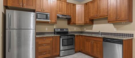 A kitchen with wooden cabinets, stainless steel appliances, and a tiled backsplash.