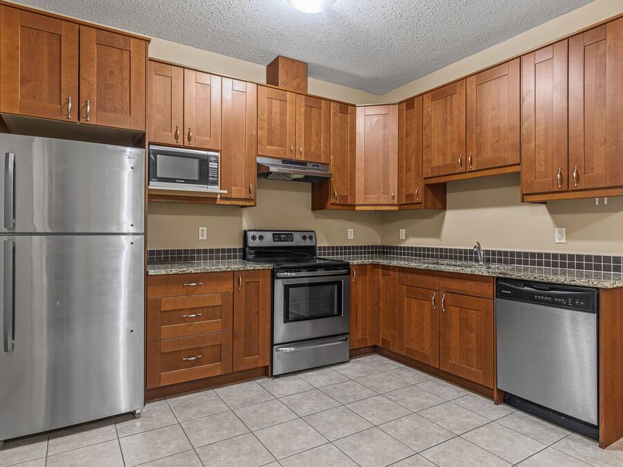 A kitchen with wooden cabinets, stainless steel appliances, and a tiled backsplash.