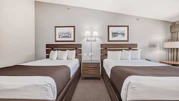 Une chambre d’hôtel avec deux lits, une petite table, une lampe et deux lampes fixées au mur.