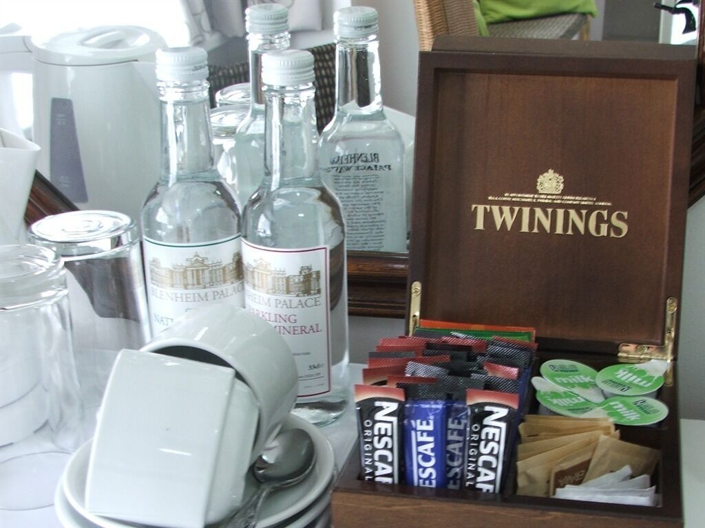 Een houten doosje met de tekst 'TWININGS', met verschillende items zoals flesjes en theezakjes.