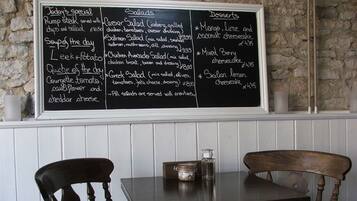 Eine Speisekarte an einer Tafel mit verschiedenen Gerichten, darunter Salate, Suppen und Desserts.