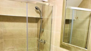 A bathroom with a glass-enclosed shower, a white sink, and a mirror. - The Chequers Inn (Amersham)