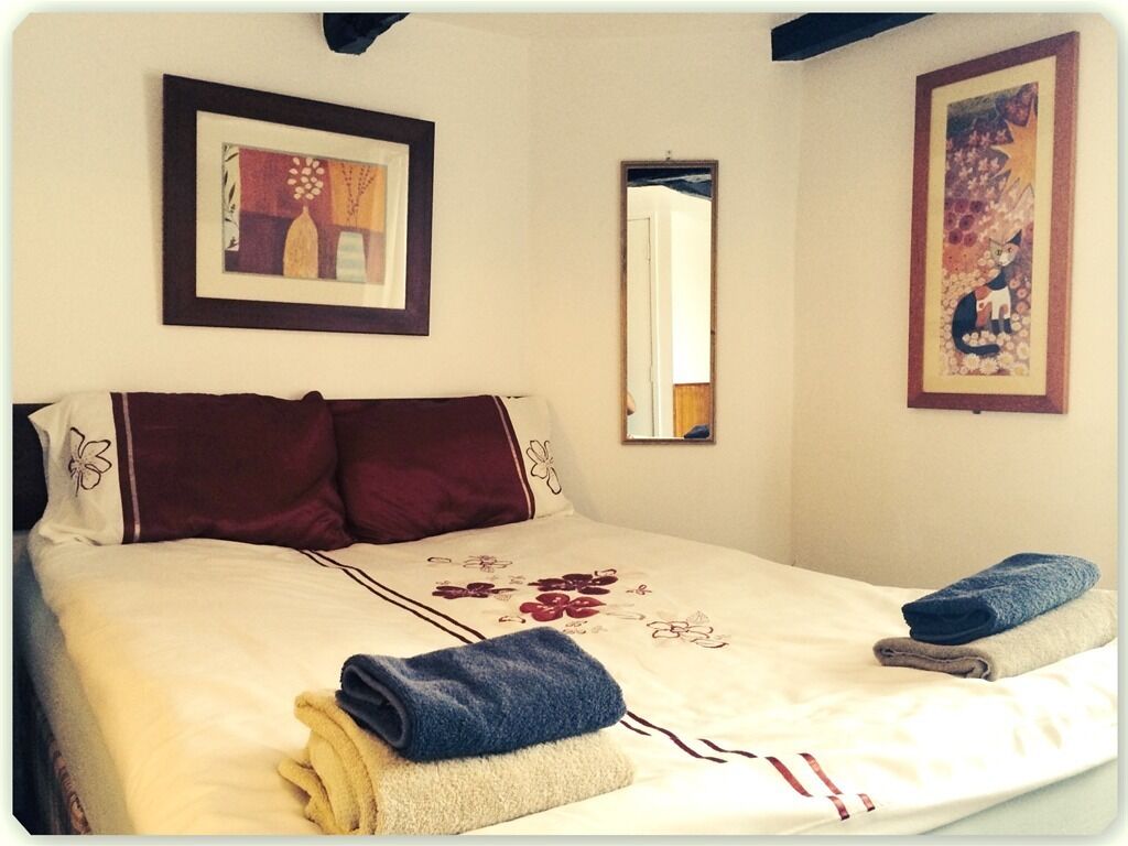A neatly made bed with a floral bedspread, two pillows, and folded towels.