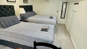 A bedroom with two beds, a skylight, a desk with a chair, and a mirror. - The Chequers Inn (Amersham)