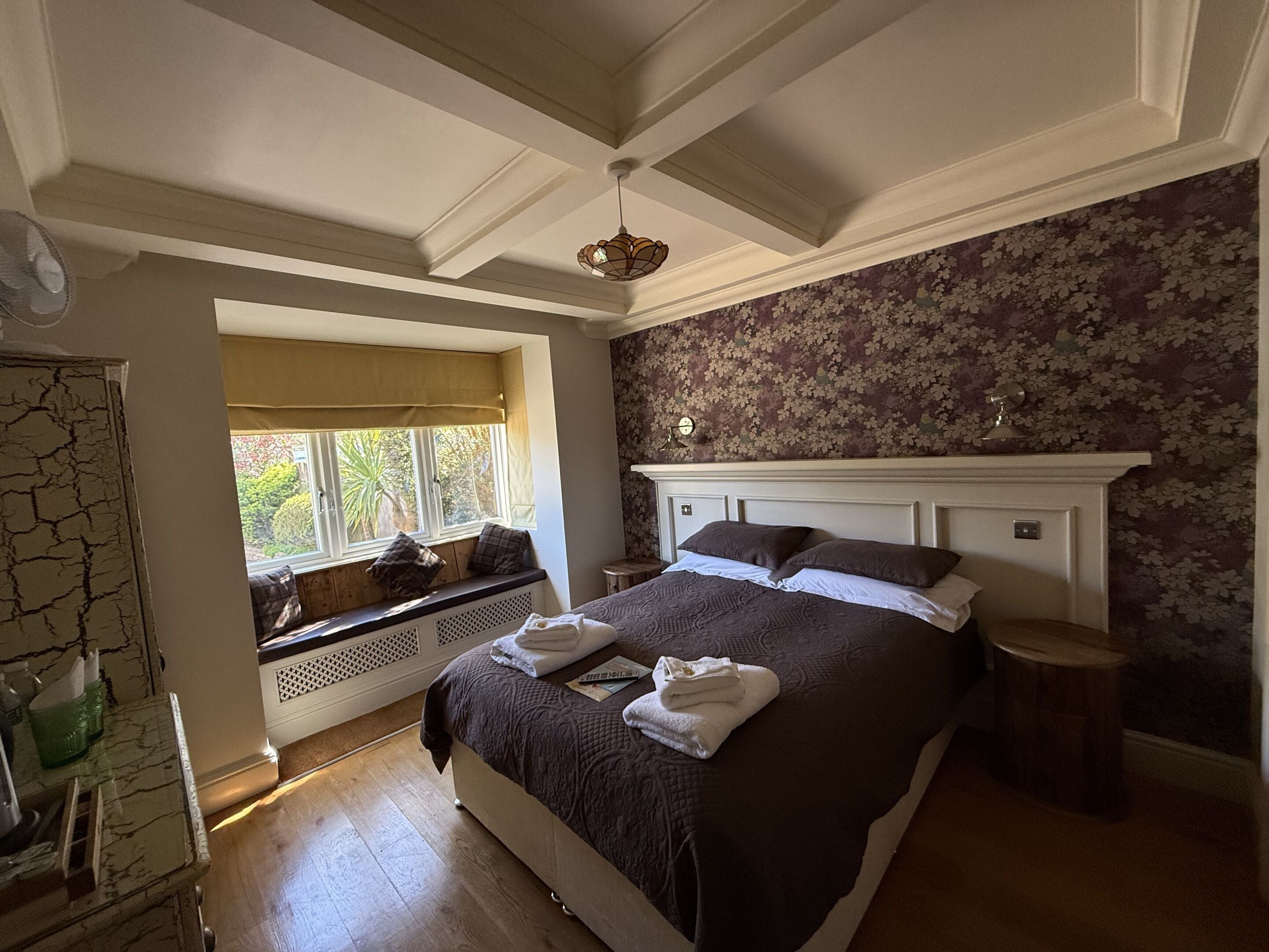 A bedroom with a large bed, a window with a view, a fireplace, and a radiator.