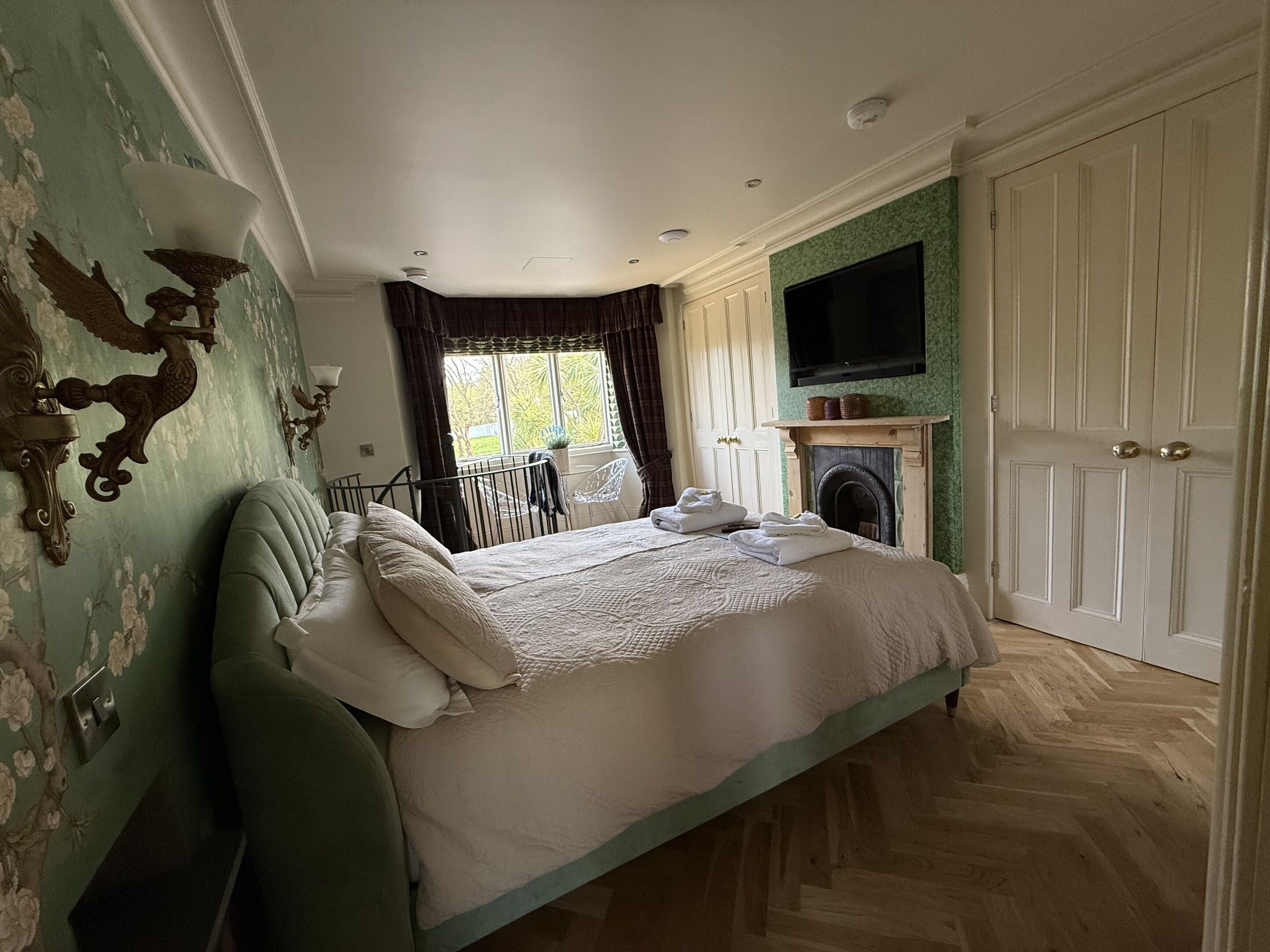 Une chambre à coucher avec un lit, une cheminée, une télévision et une fenêtre avec des rideaux.