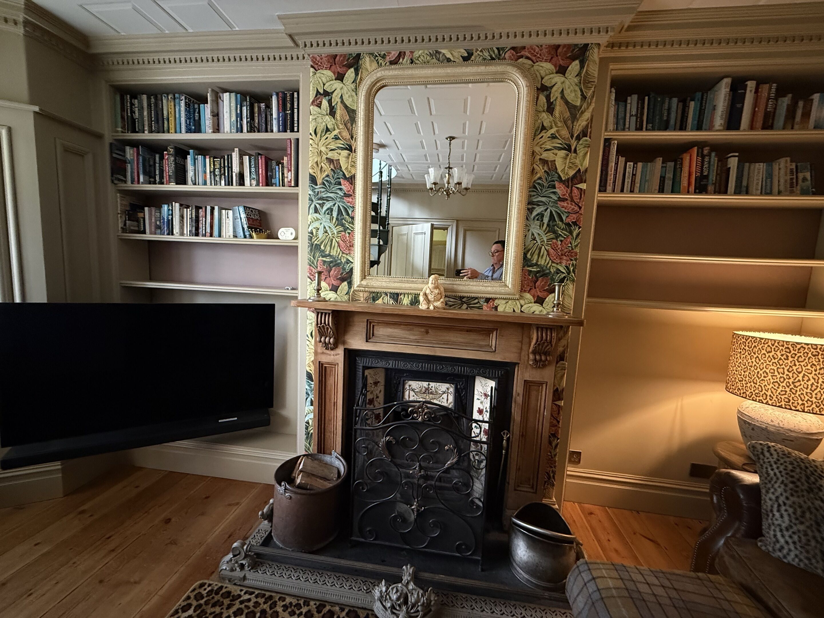 Un salon avec une cheminée, des étagères à livres, un téléviseur et un tapis à motifs léopard.
