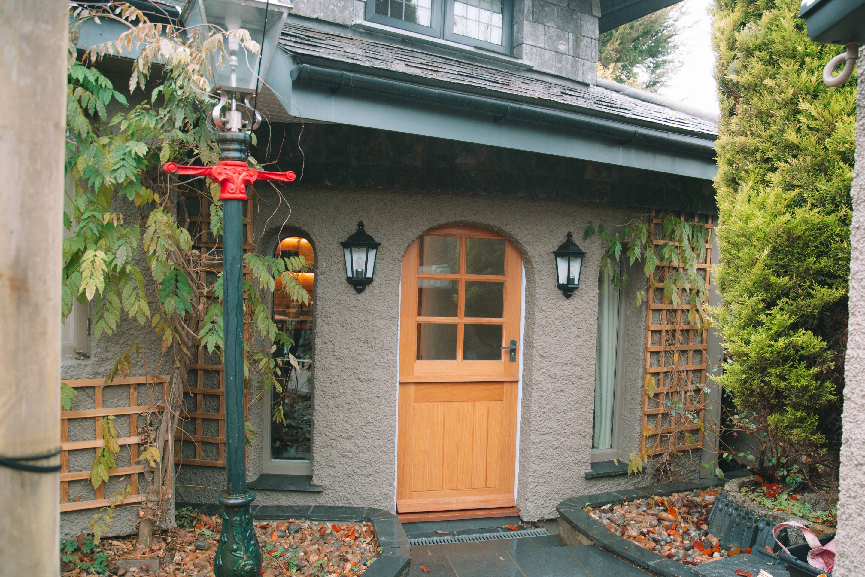 A rustic building with a wooden door, a green fence, and a stone wall.