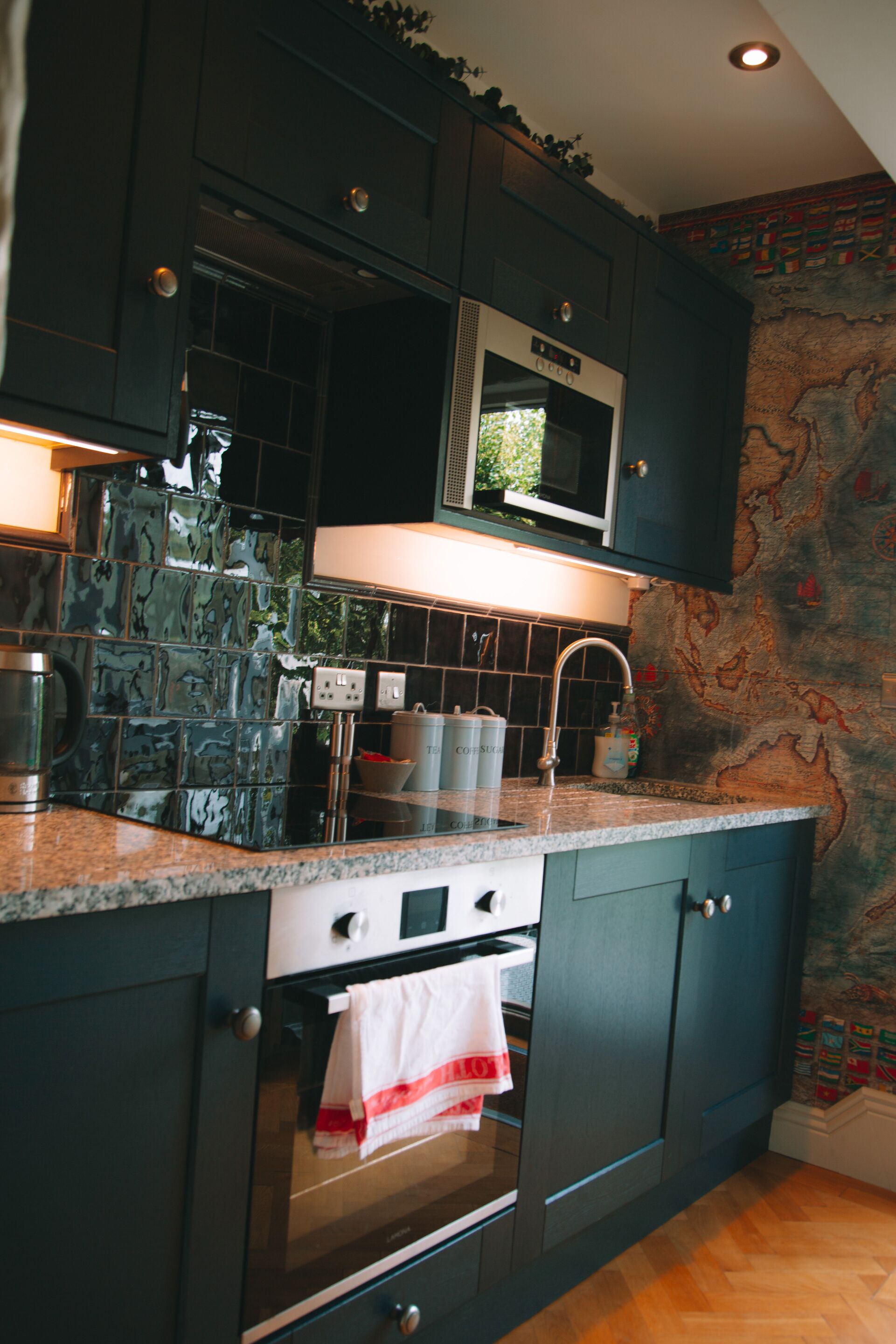 A kitchen with dark cabinets, a microwave, a stove, and a tiled backsplash.