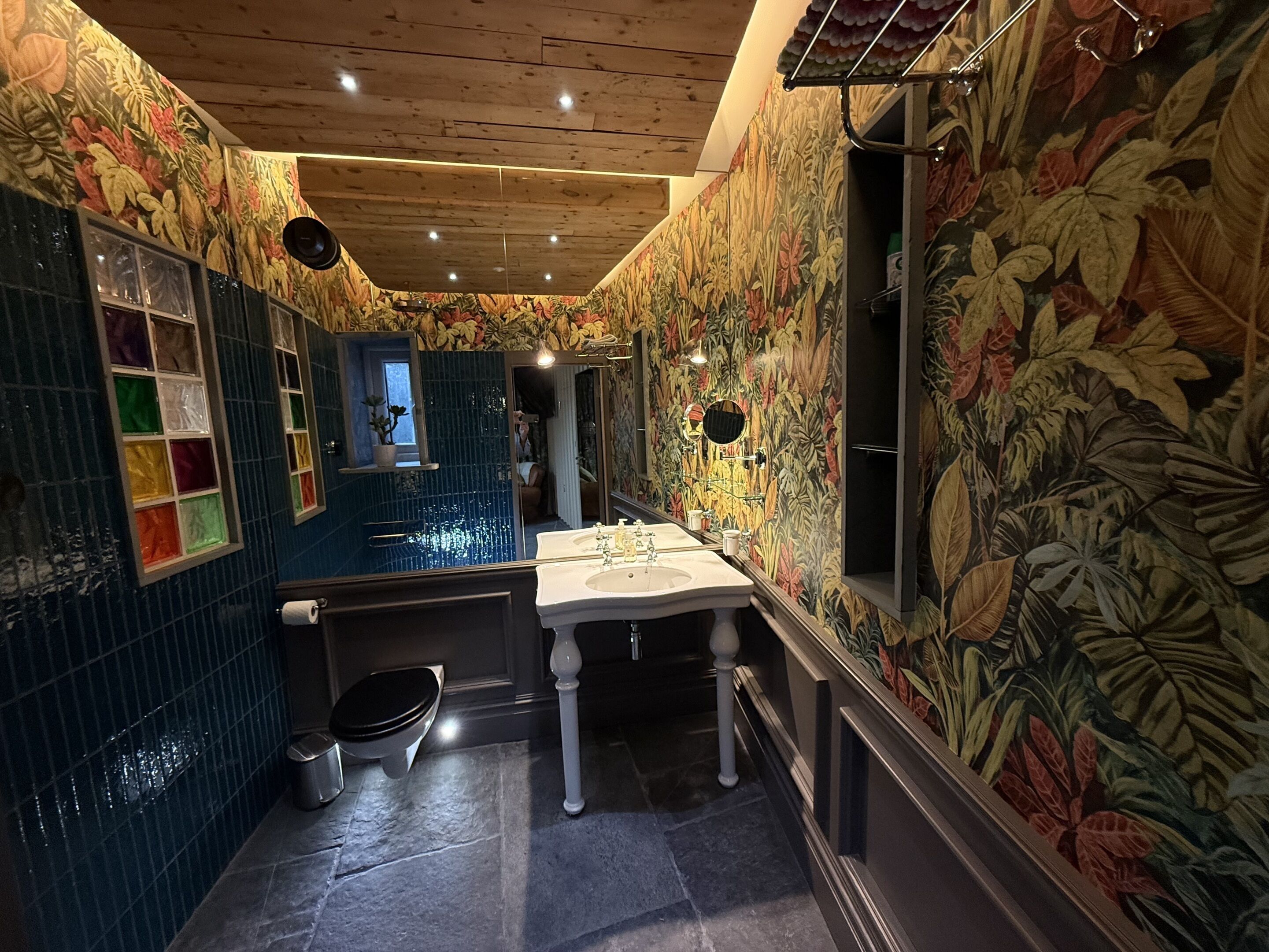 A bathroom with a tiled floor, a sink, a toilet, and a mirror.