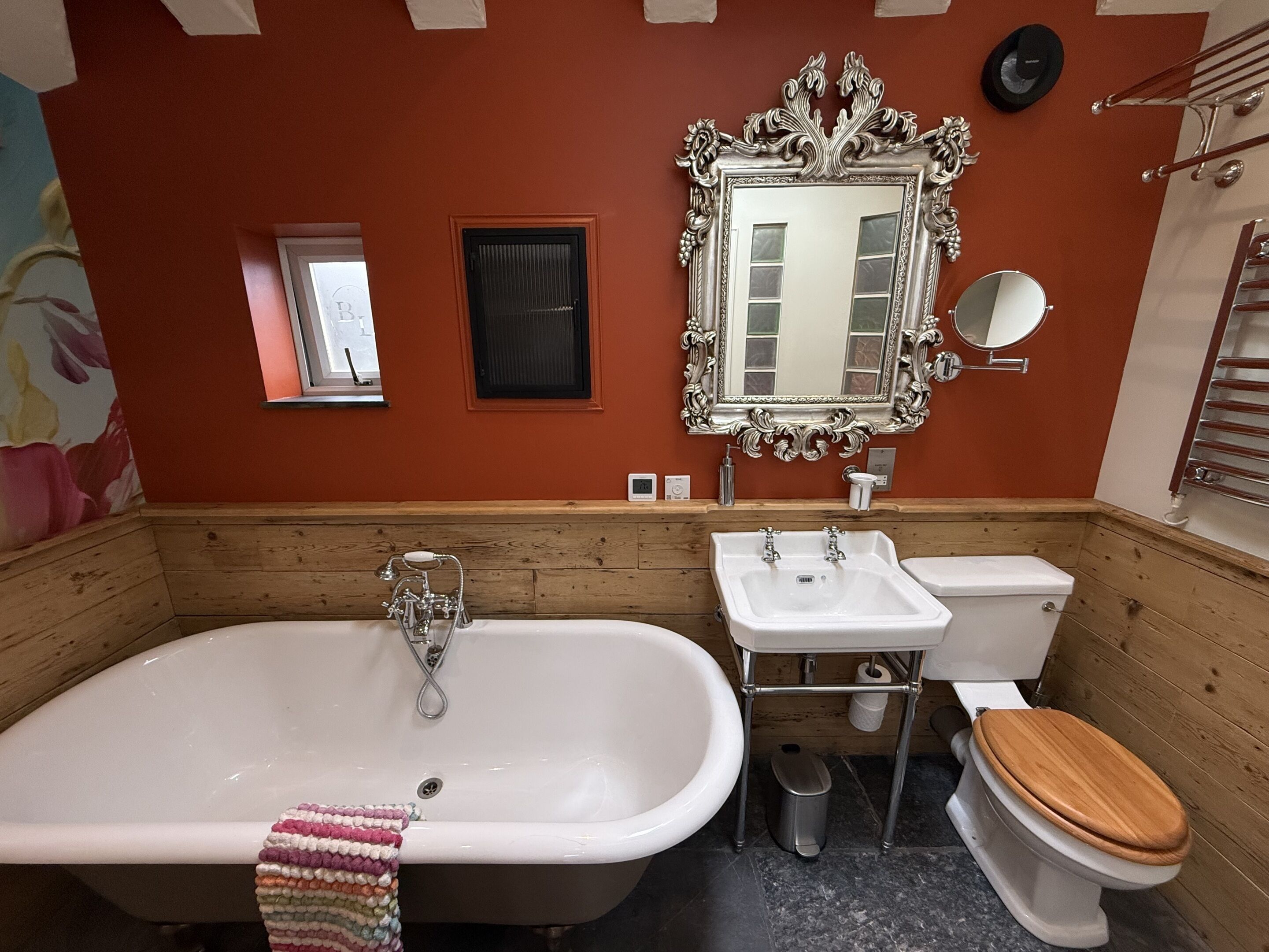 A bathroom with a bathtub, two sinks, a toilet, and a mirror.