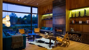 Un salón amplio con un gran ventanal, chimenea y muebles de madera.