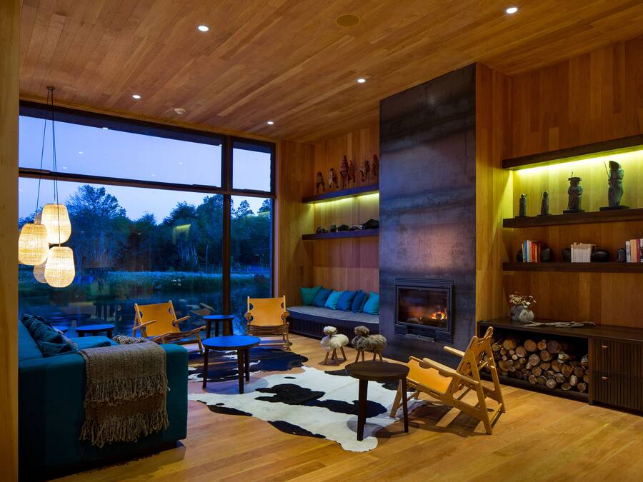 Un salón amplio con un gran ventanal, chimenea y muebles de madera.