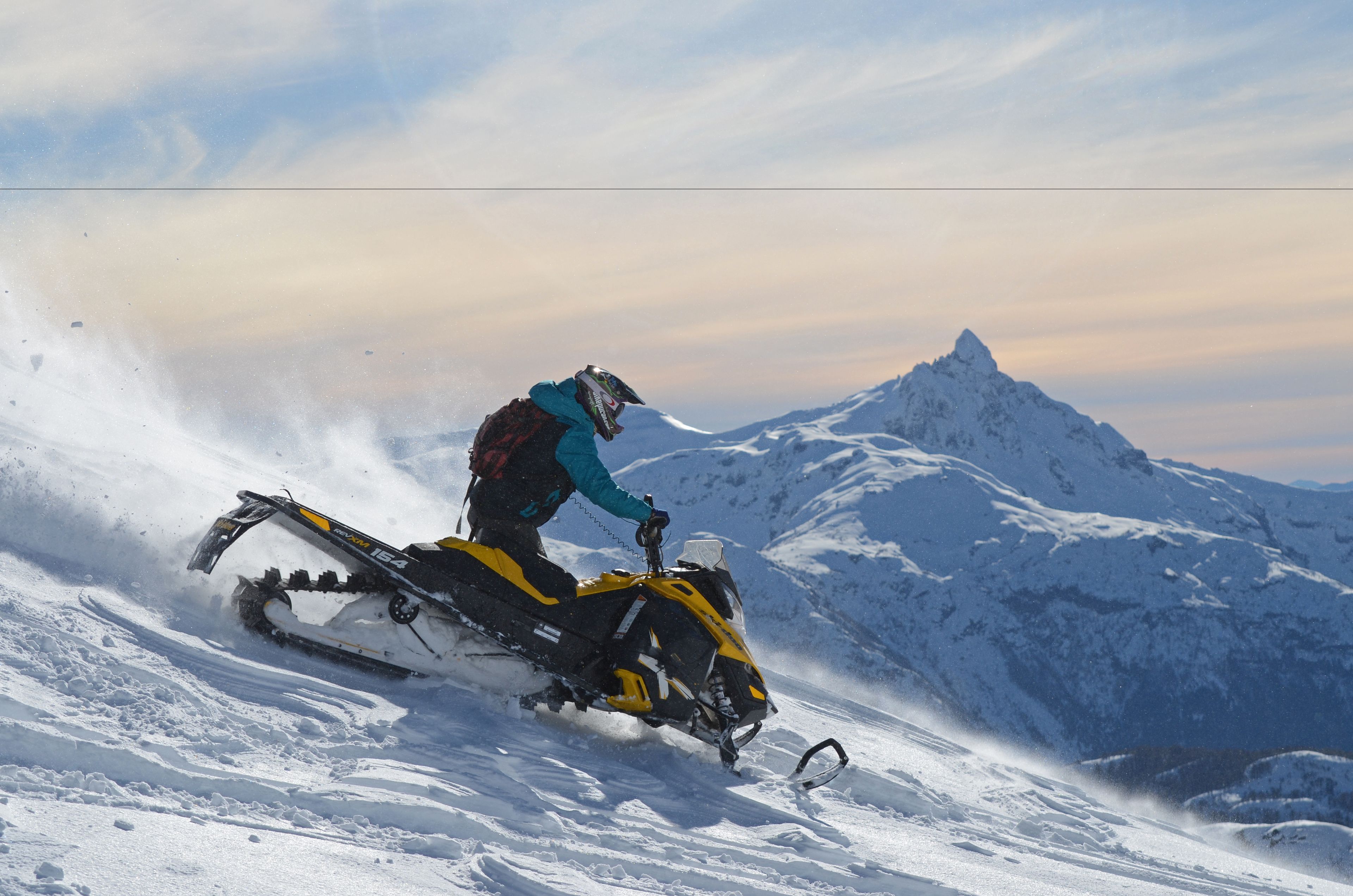 A snowmobile on a snowy slope with a mountain in the background.