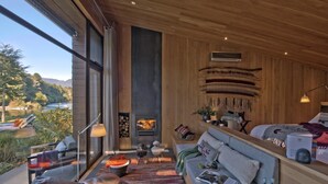 Una sala de estar moderna con chimenea, ventanas amplias y vistas al exterior.