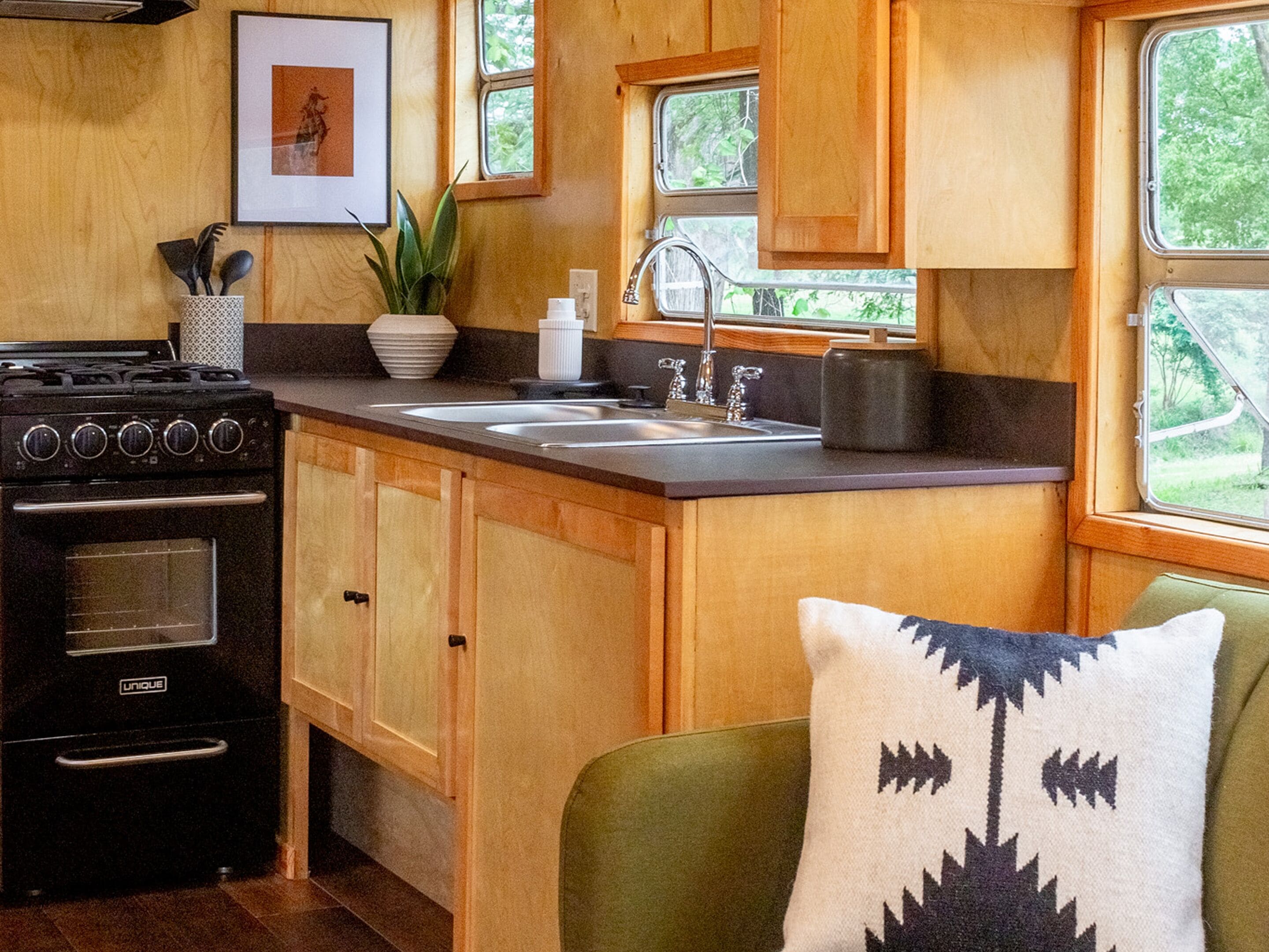 A compact kitchen with wooden cabinets, a stove, and a sink.