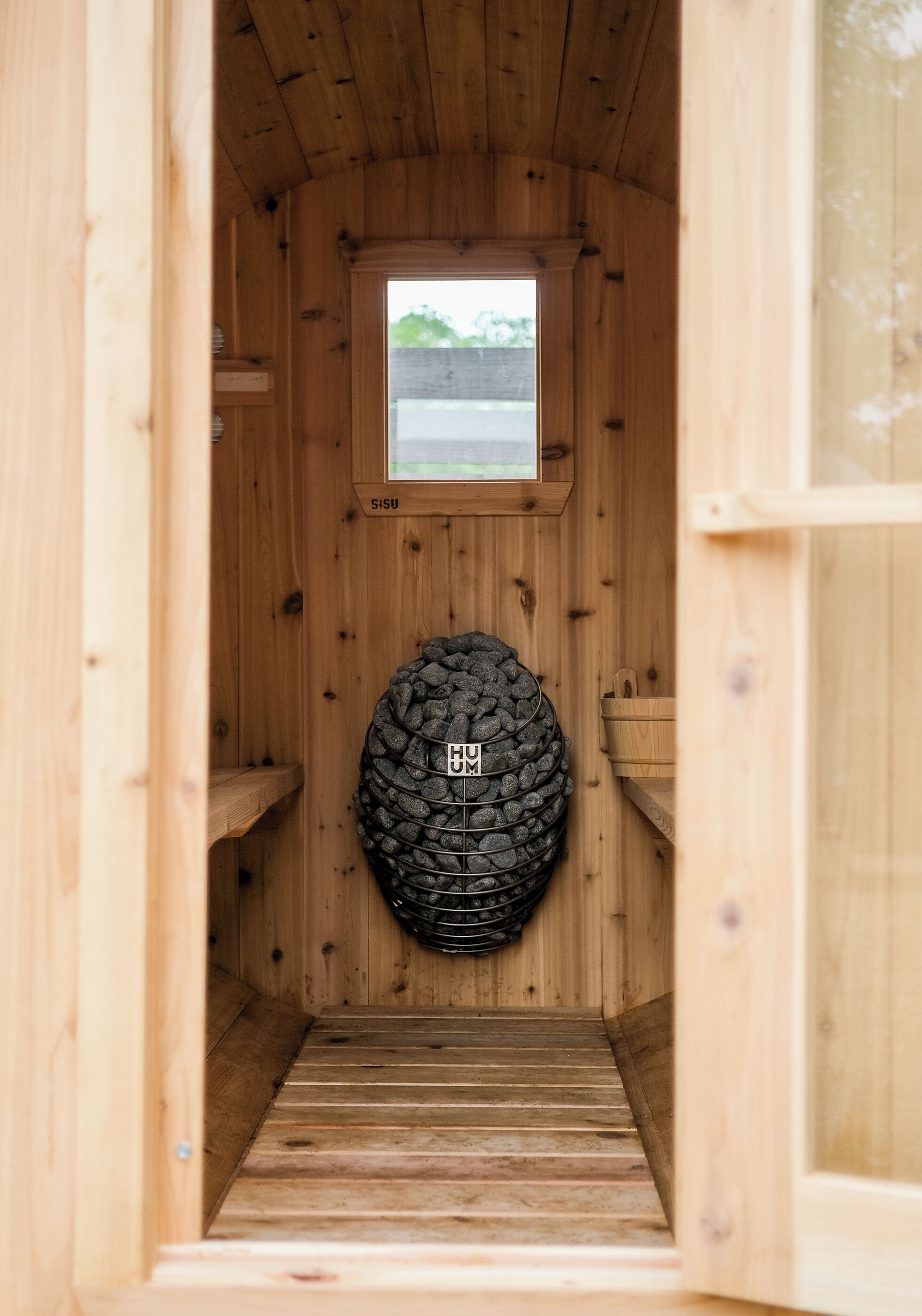 Een sauna met houten wanden, een stenen muur en een klein raam aan de bovenkant.