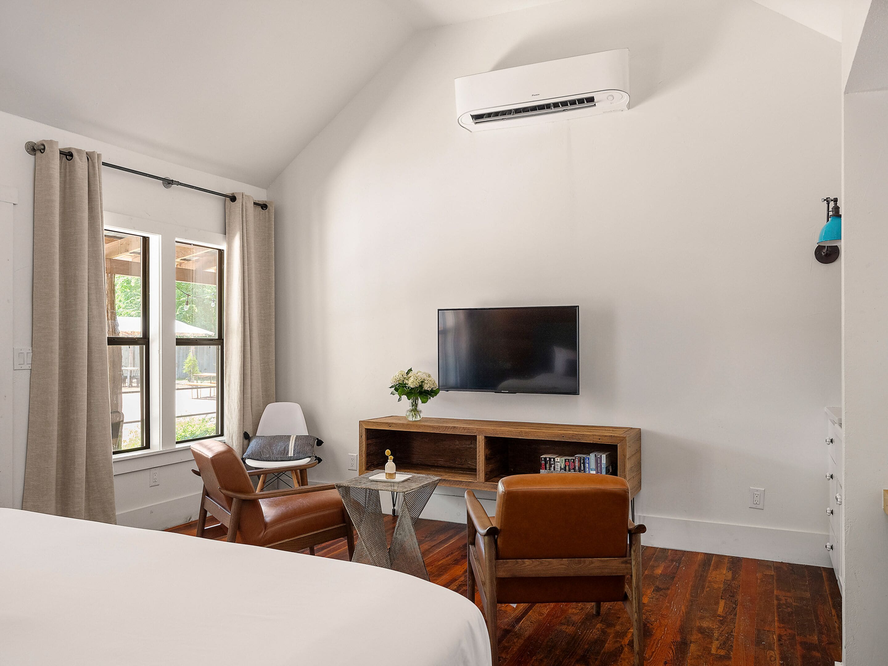 Ein Hotelzimmer mit einem Bett, einem Schreibtisch mit Stuhl, einem Fernseher und einer Klimaanlage.