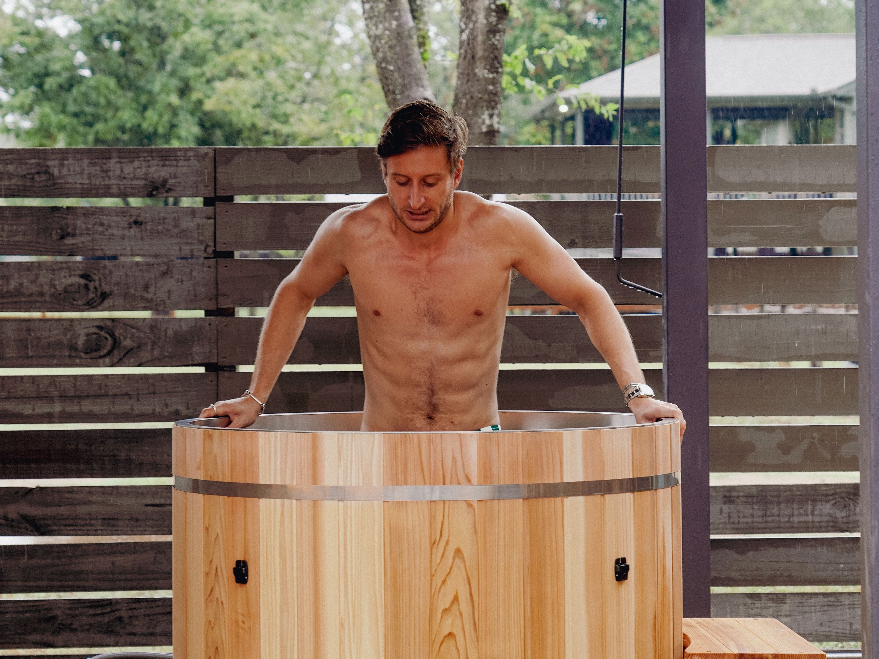 Un homme se tient debout à l’intérieur d’un sauna en bois.