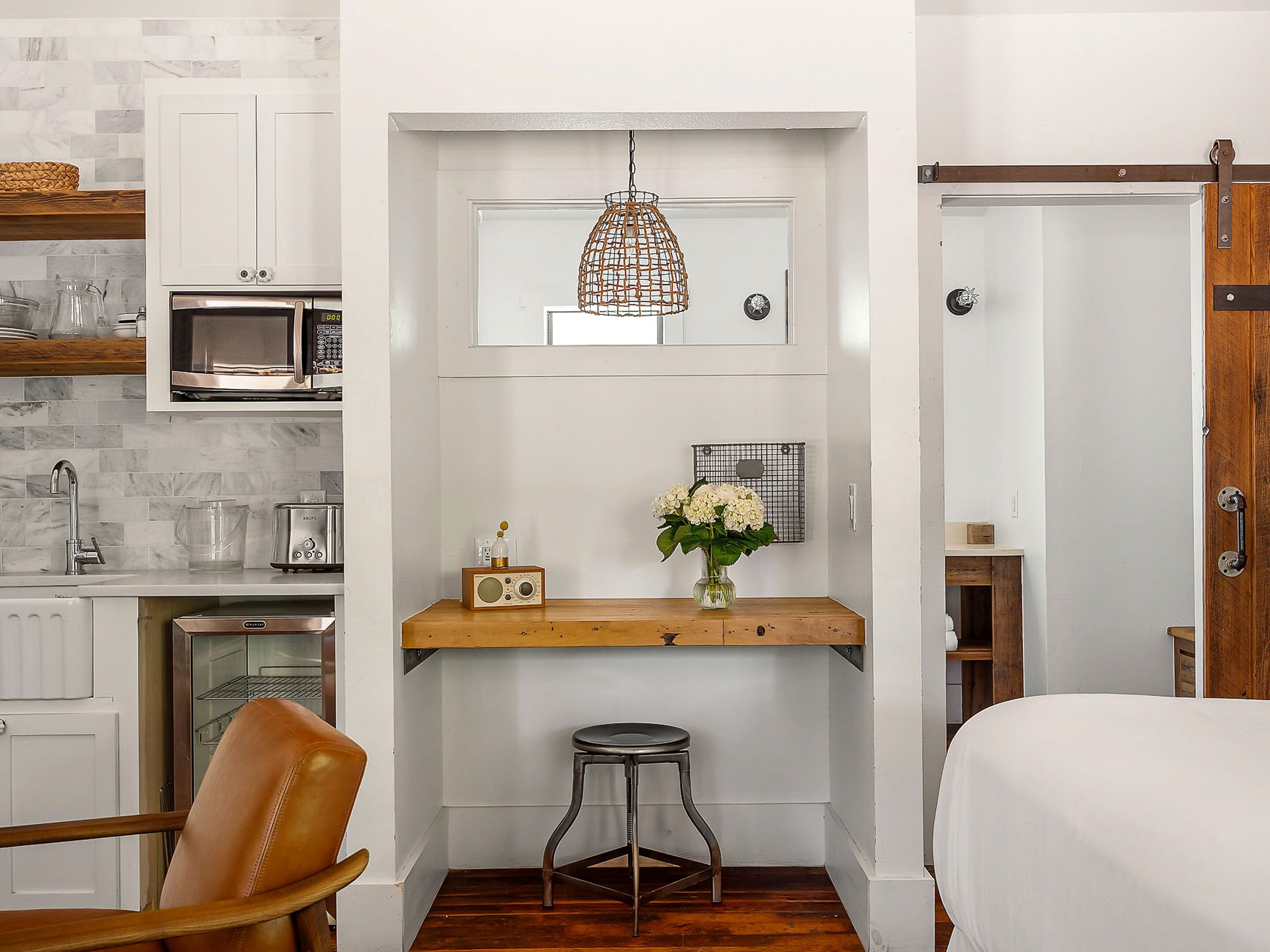 A compact kitchen with a microwave, toaster, and hanging pendant light.