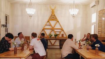 Un espace repas avec des bancs et des tables en bois, une décoration murale en bois et des lustres suspendus.