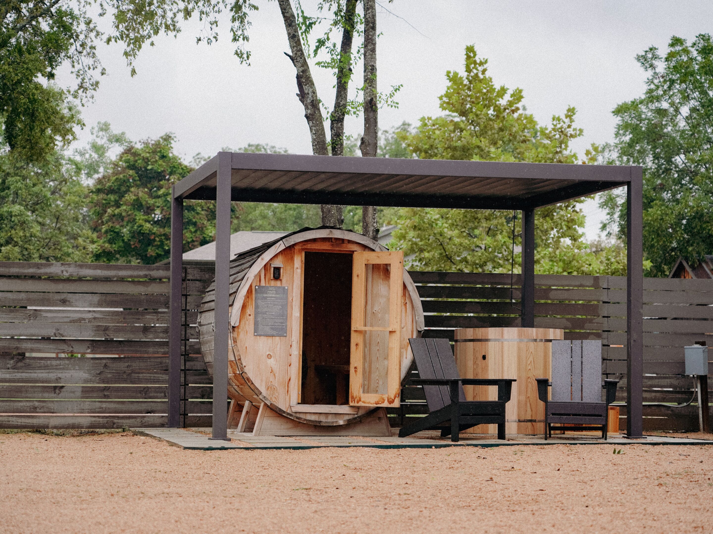 A rustic wooden structure with a covered entrance, a bench, and a table outside.