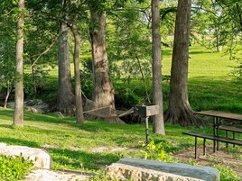 Een park met een hangmat, picknicktafel en stenen banken.