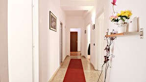 A hallway with a red carpet, white walls, and a door at the end. - Stairs of Trastevere (Rome)