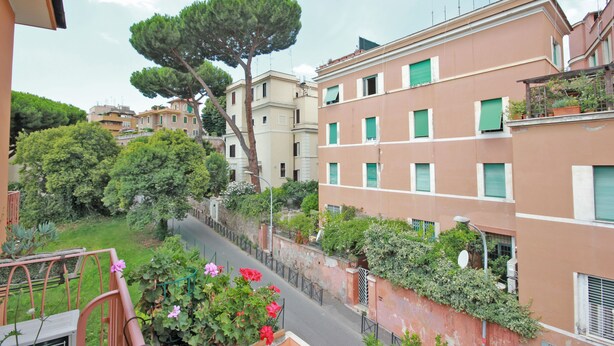 A residential building with multiple balconies, a tree, and a street view. - Stairs of Trastevere (Rome)