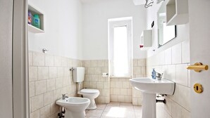 A bathroom with two toilets, a sink, and a window. - Stairs of Trastevere (Rome)