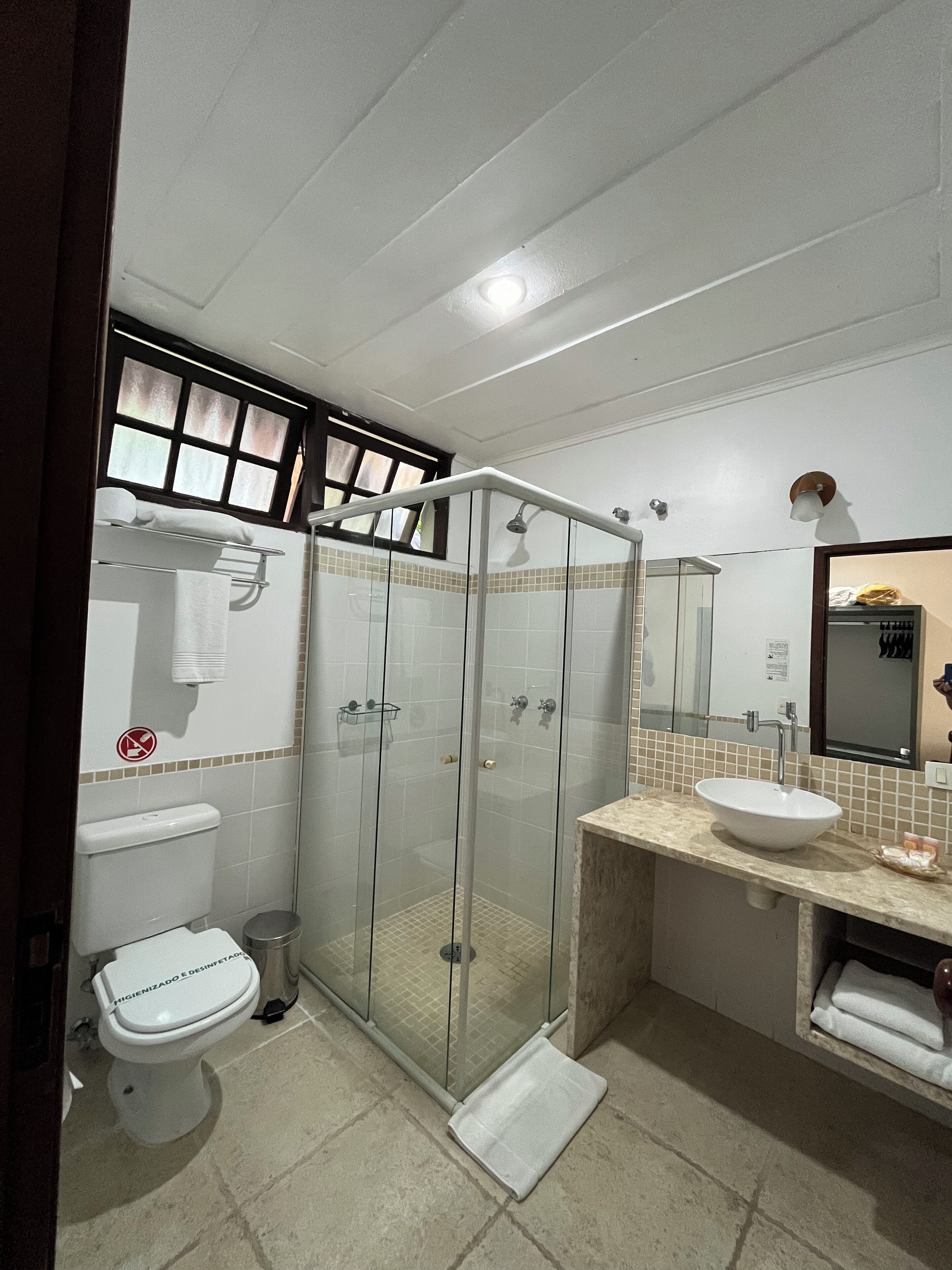 Un bagno con doccia vetrata, un water, un lavandino e uno specchio.