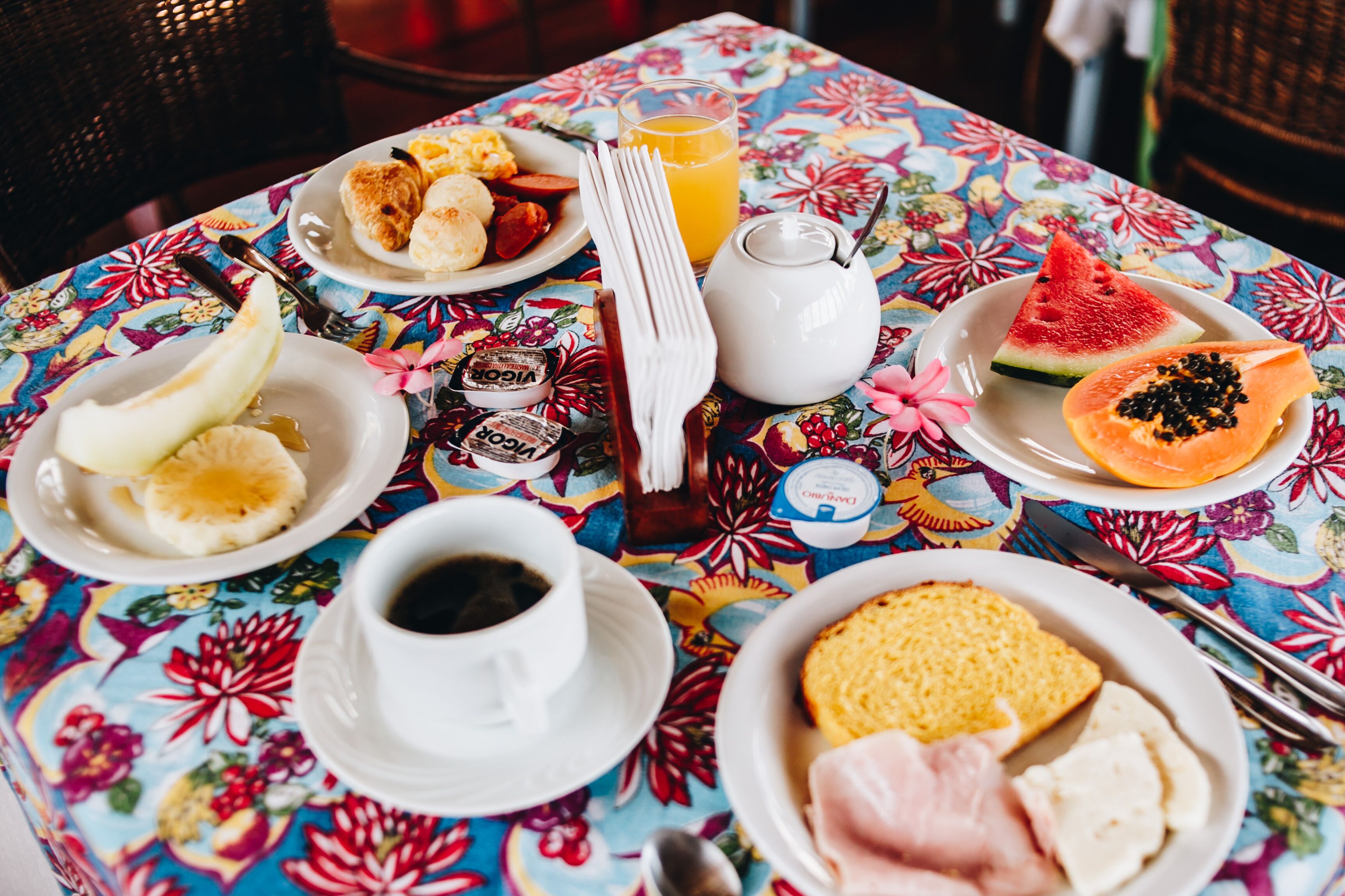 A table with breakfast items including toast, eggs, and fruit, along with a jug of juice and a cup of coffee.