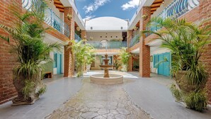 A spacious atrium with a central fountain, surrounded by brick walls and potted plants.