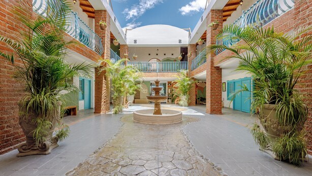 A spacious atrium with a central fountain, surrounded by brick walls and potted plants.