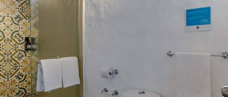 A bathroom with a toilet, a glass shower enclosure, a towel rack, and a wall-mounted light fixture.
