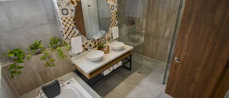 Un baño moderno con bañera, dos lavamanos, un espejo grande y zona de ducha.
