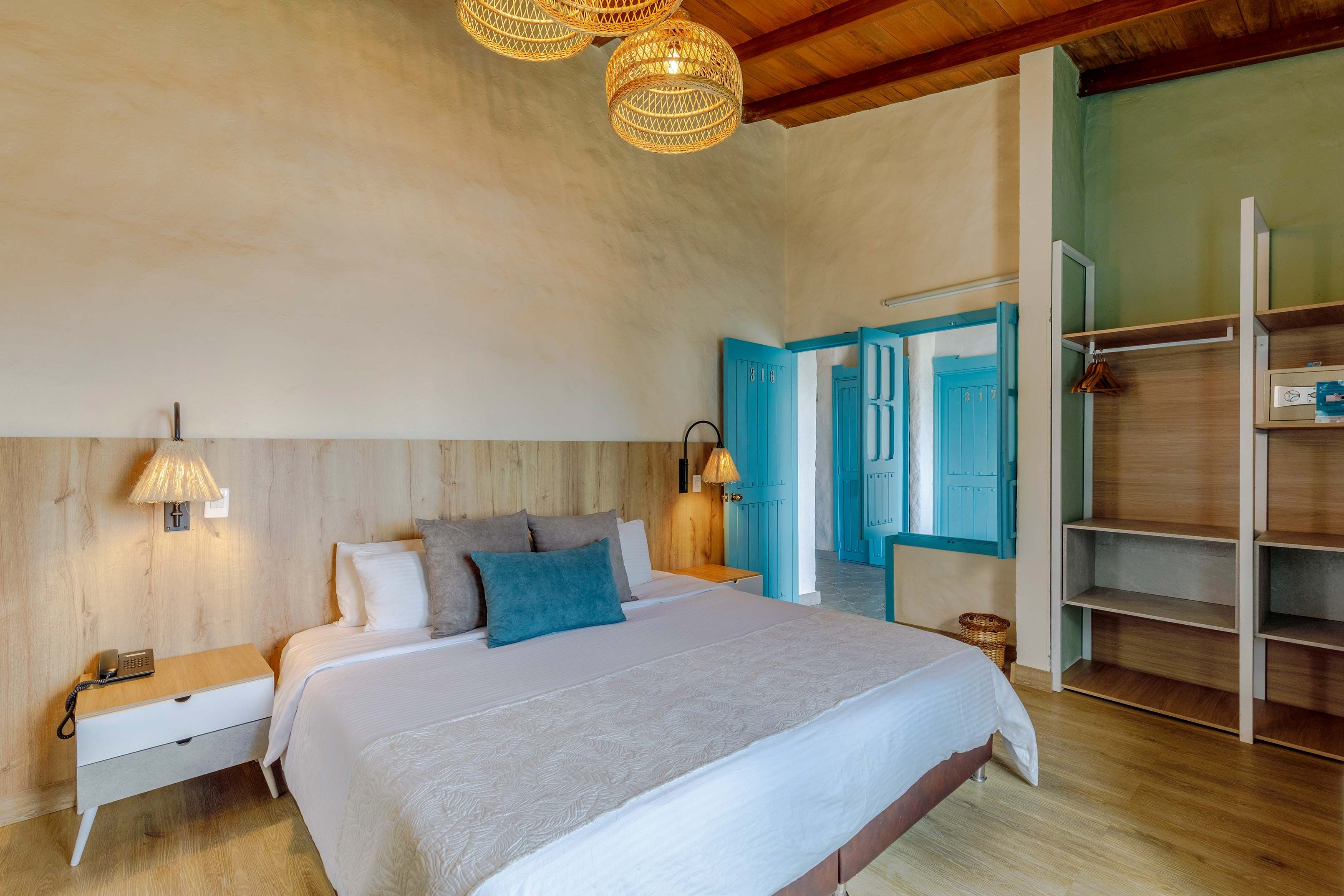 Un dormitorio con cama, mesita de noche, lámpara, armario y una puerta con número.
