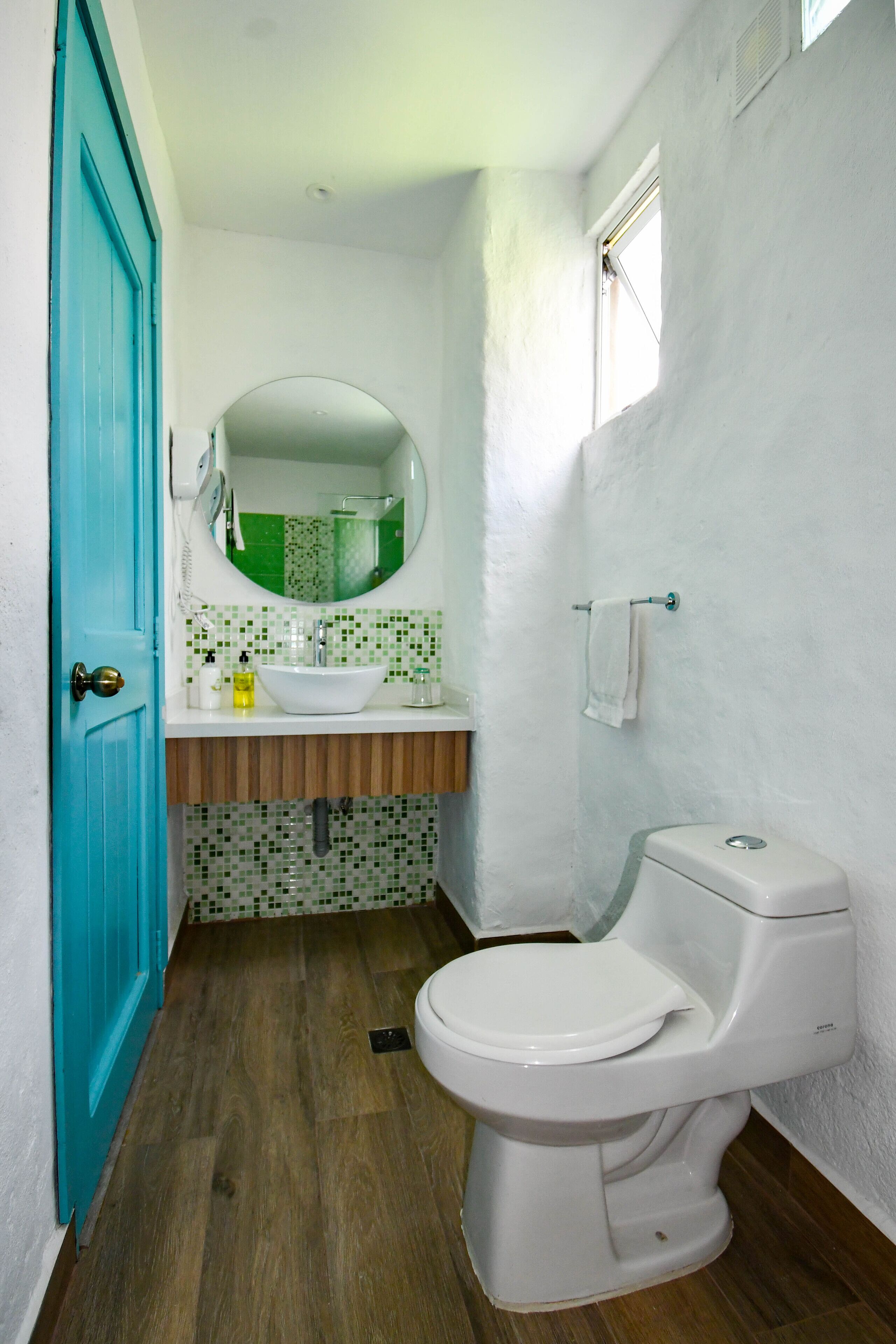 A bathroom with a white toilet, a sink with a mirror above it, and a blue door.