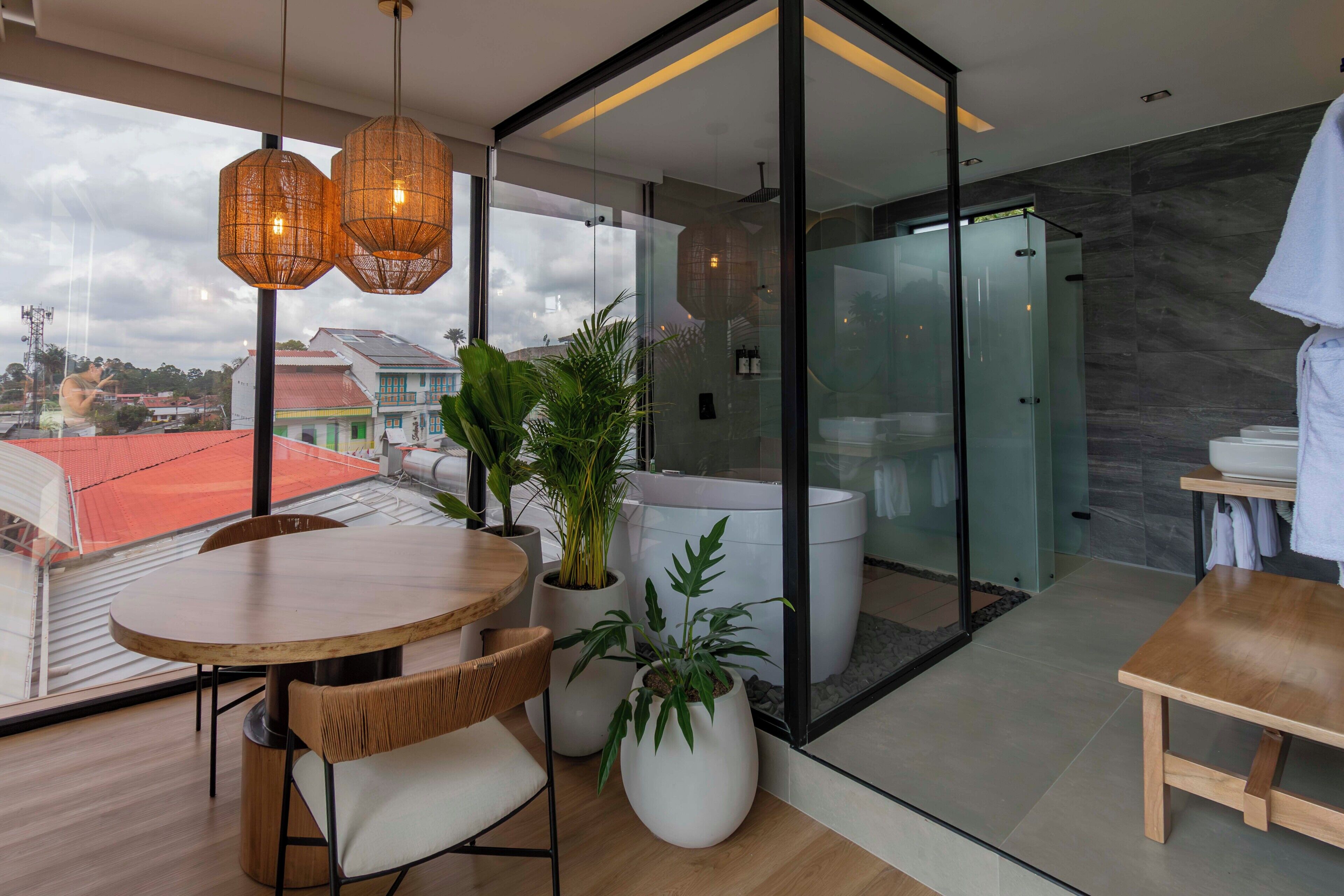 A modern interior with a dining area, a glass-enclosed shower, and a view of the cityscape.