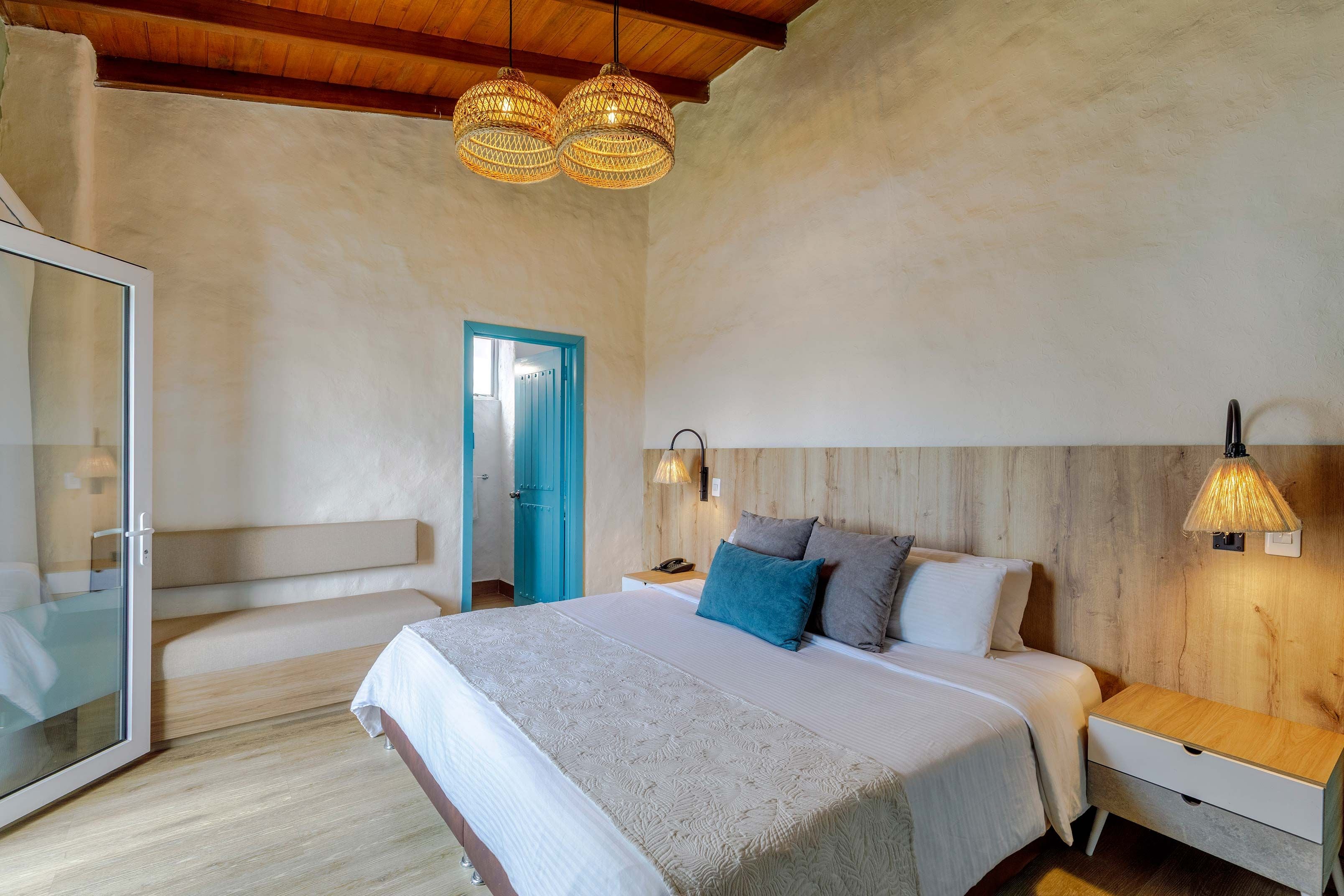 A bedroom with a bed, bedside tables, a wardrobe, and a door leading to another room.