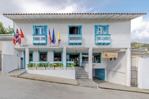 A white building with blue balconies and multiple flags.