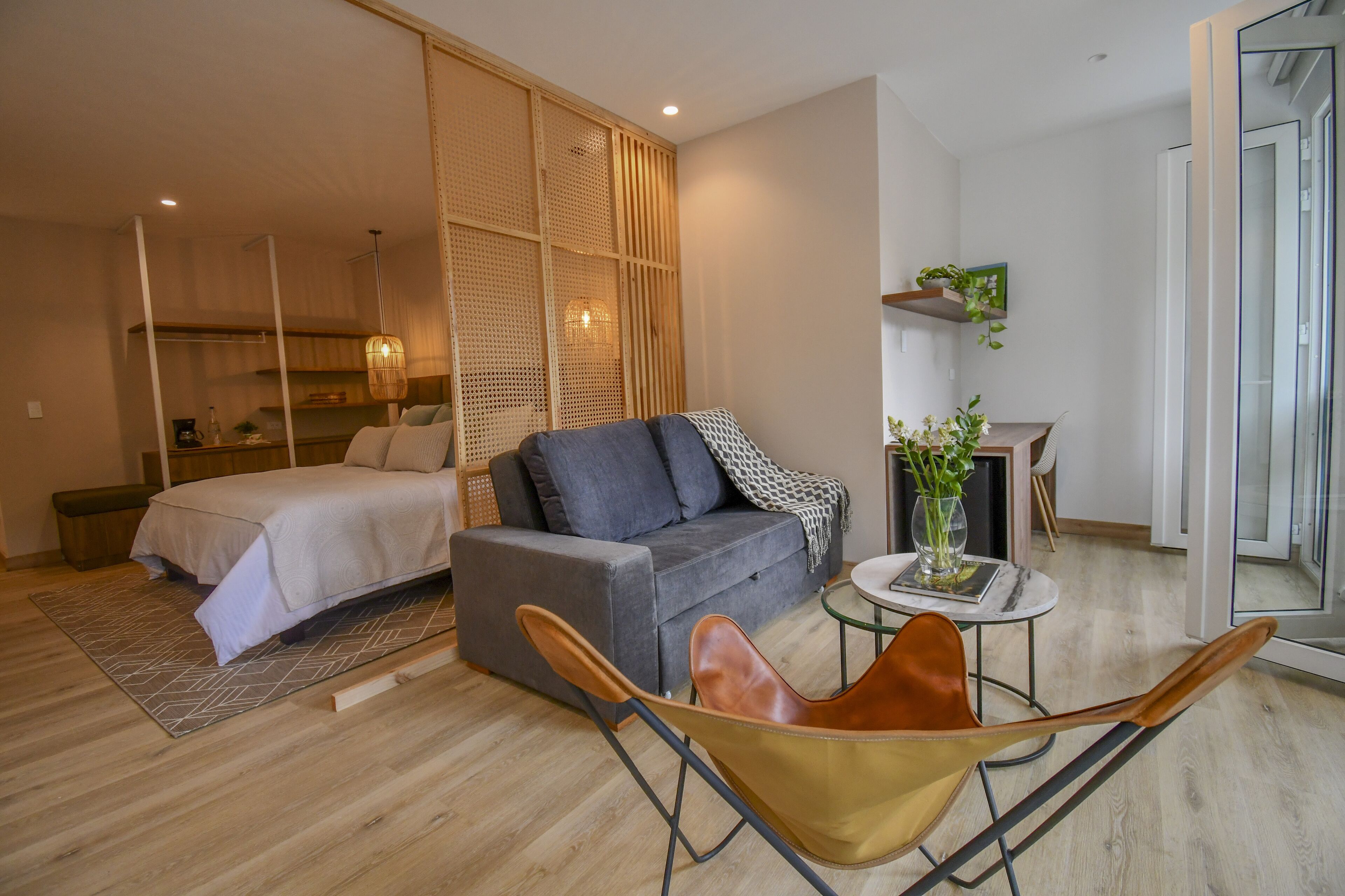 A modern living room with a bed, sofa, and a dining area with a small table and chairs.