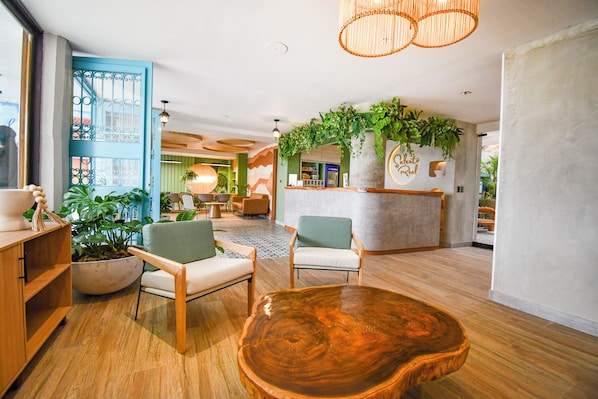 A spacious lobby with a reception desk, wooden chairs, a large wooden coffee table, and potted plants. - Hotel Salento Real Eje Cafetero (Salento)
